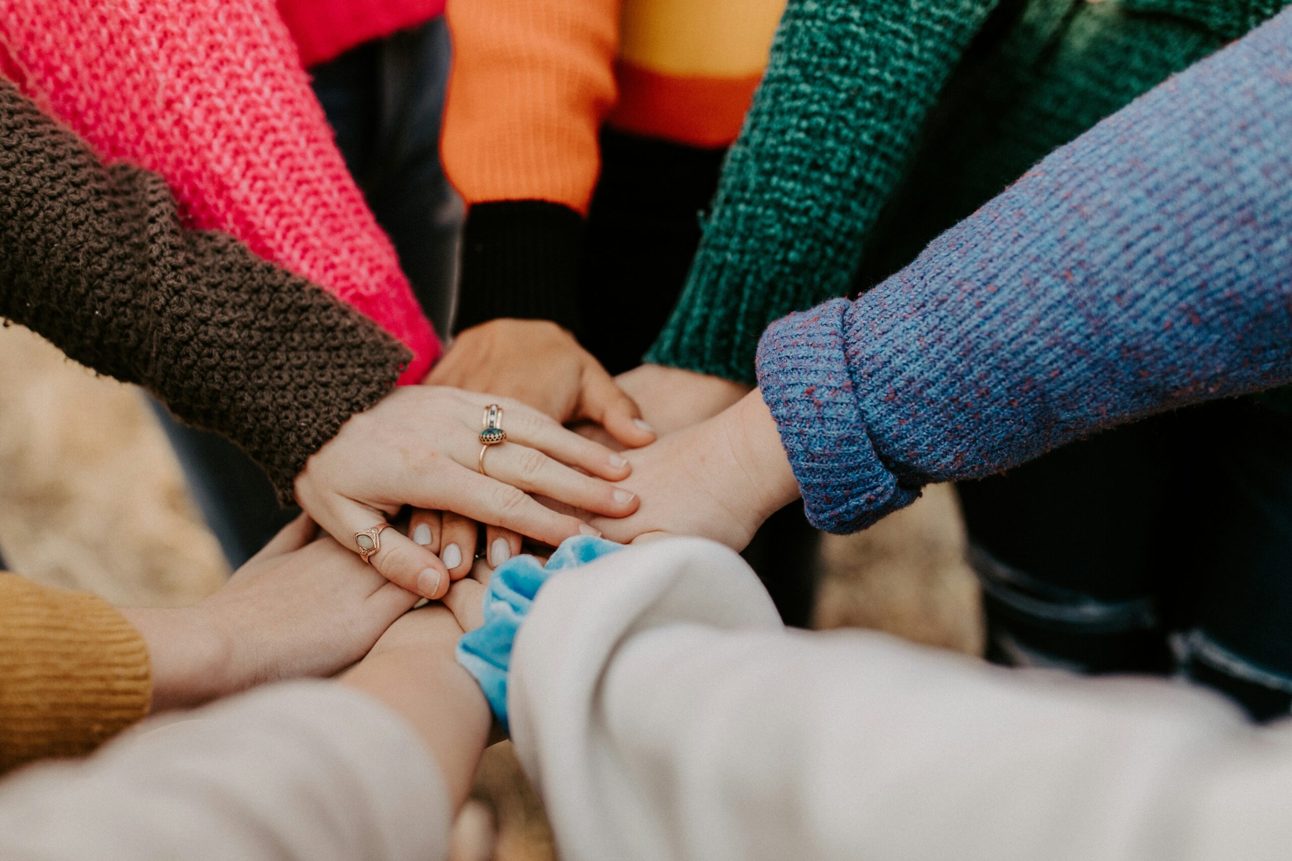 A group of people put their hands into the centre to form a circle