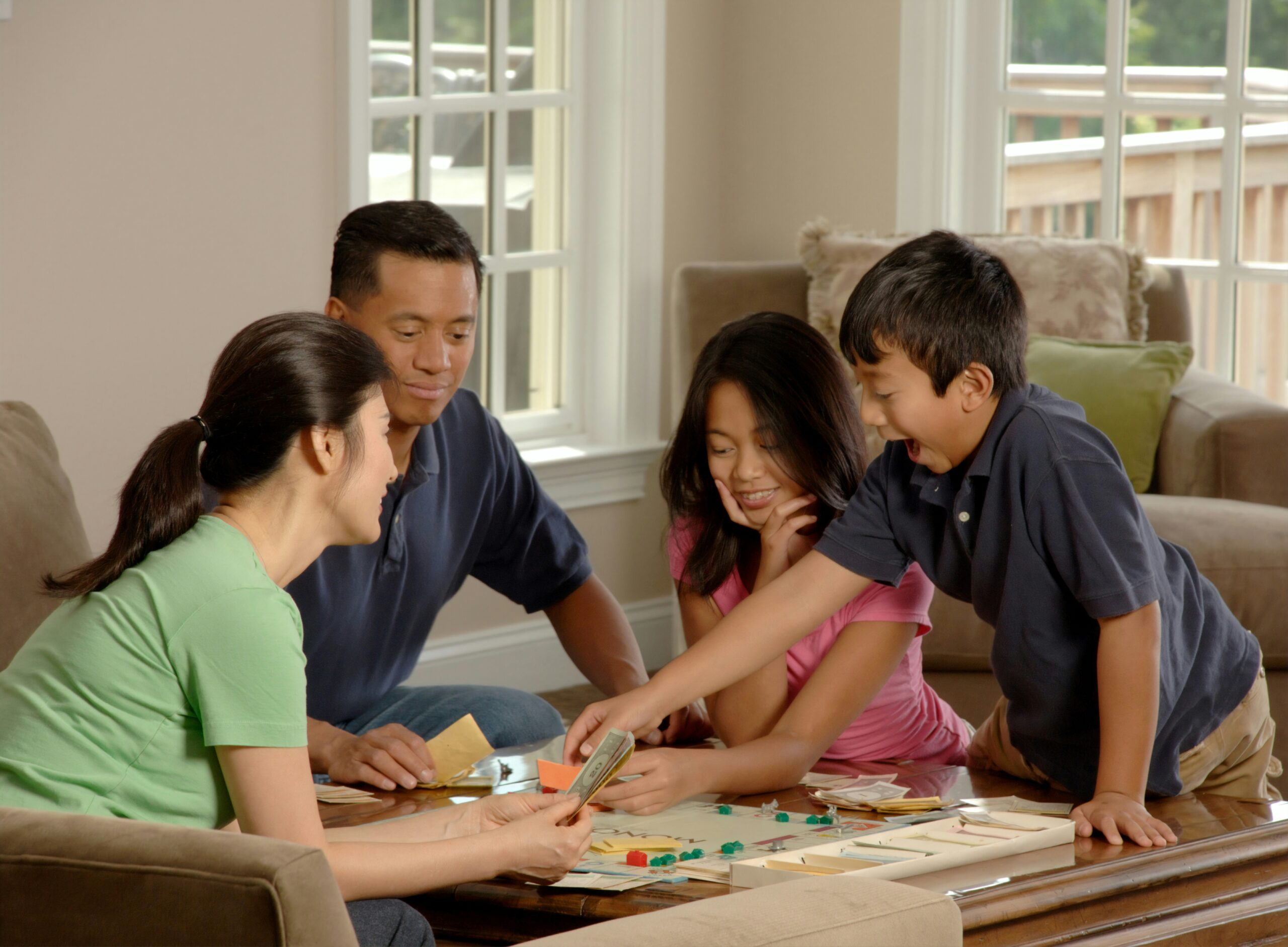 Family of a man, a woman, a boy and a girl playing a board game round the table.