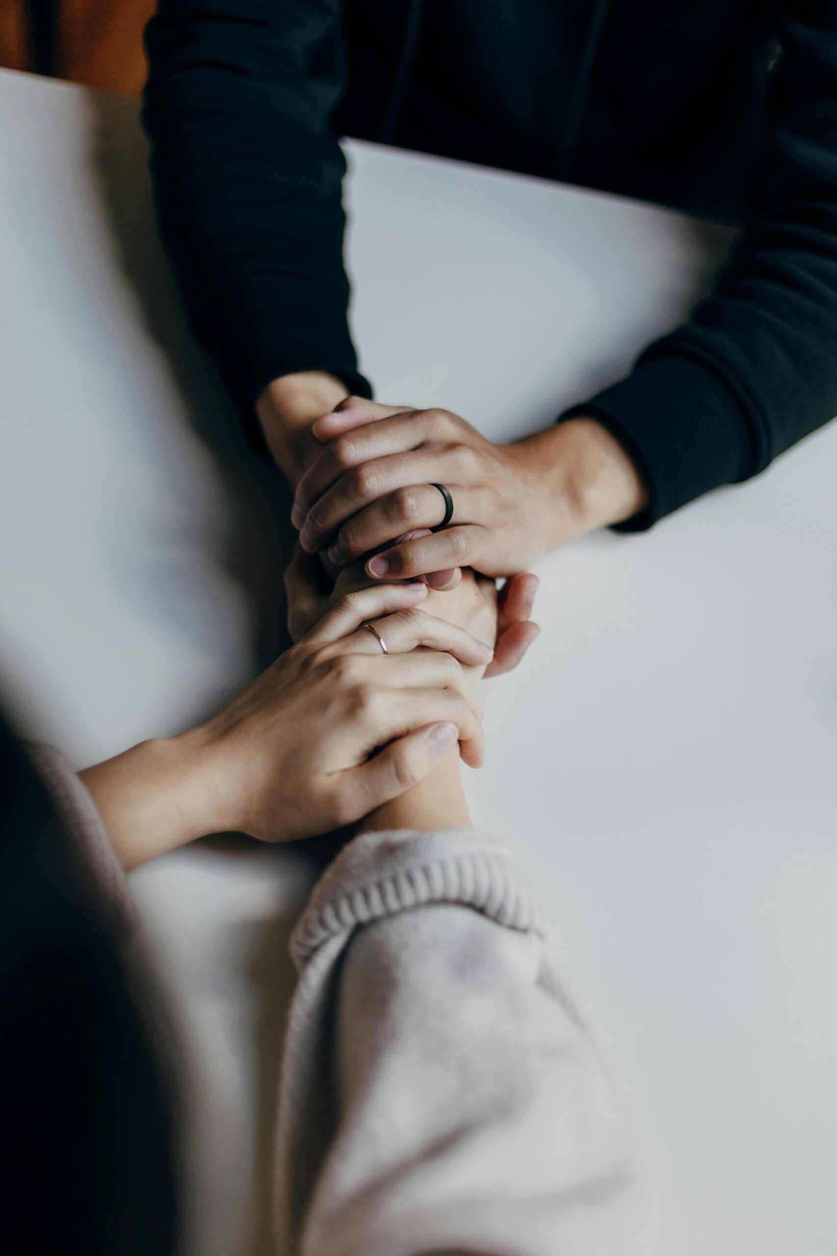 Two hands are being held, reaching across a table.